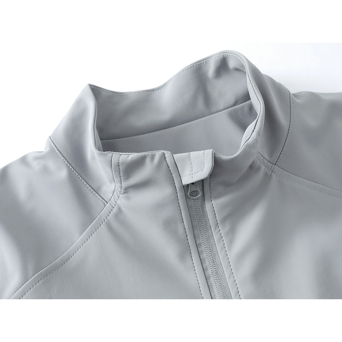 Close-up of a light gray jacket's stand collar and front zipper with a protective flap.