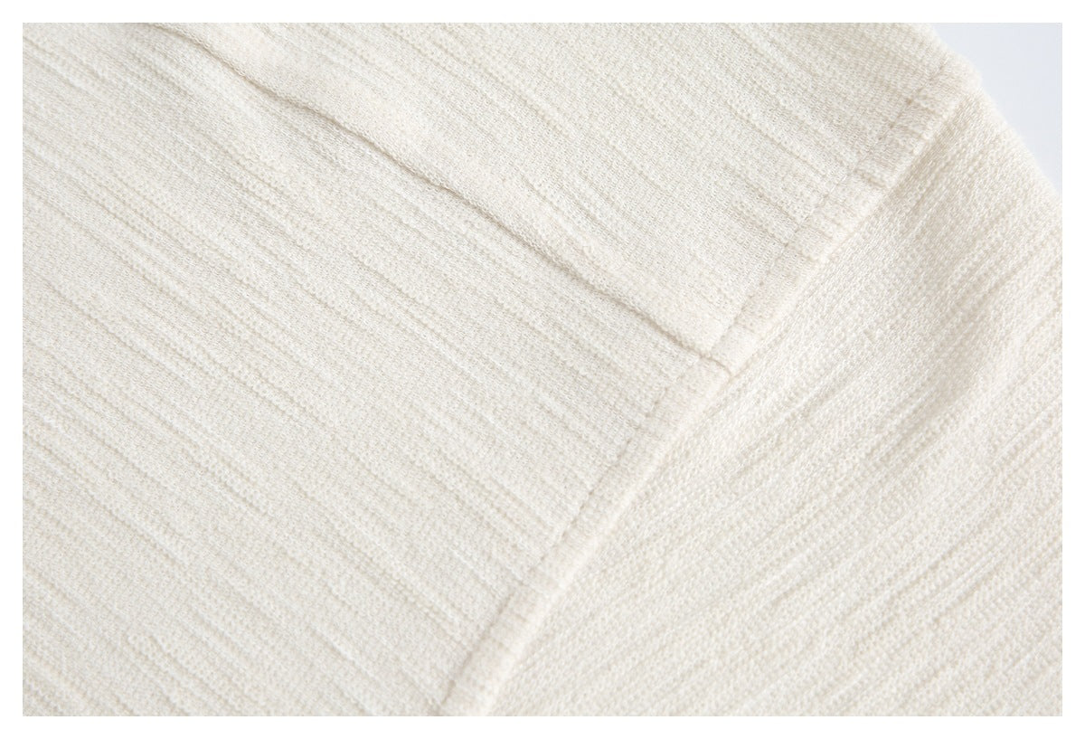 Close-up of ivory knit fabric showing intersecting seams and textured stitching.