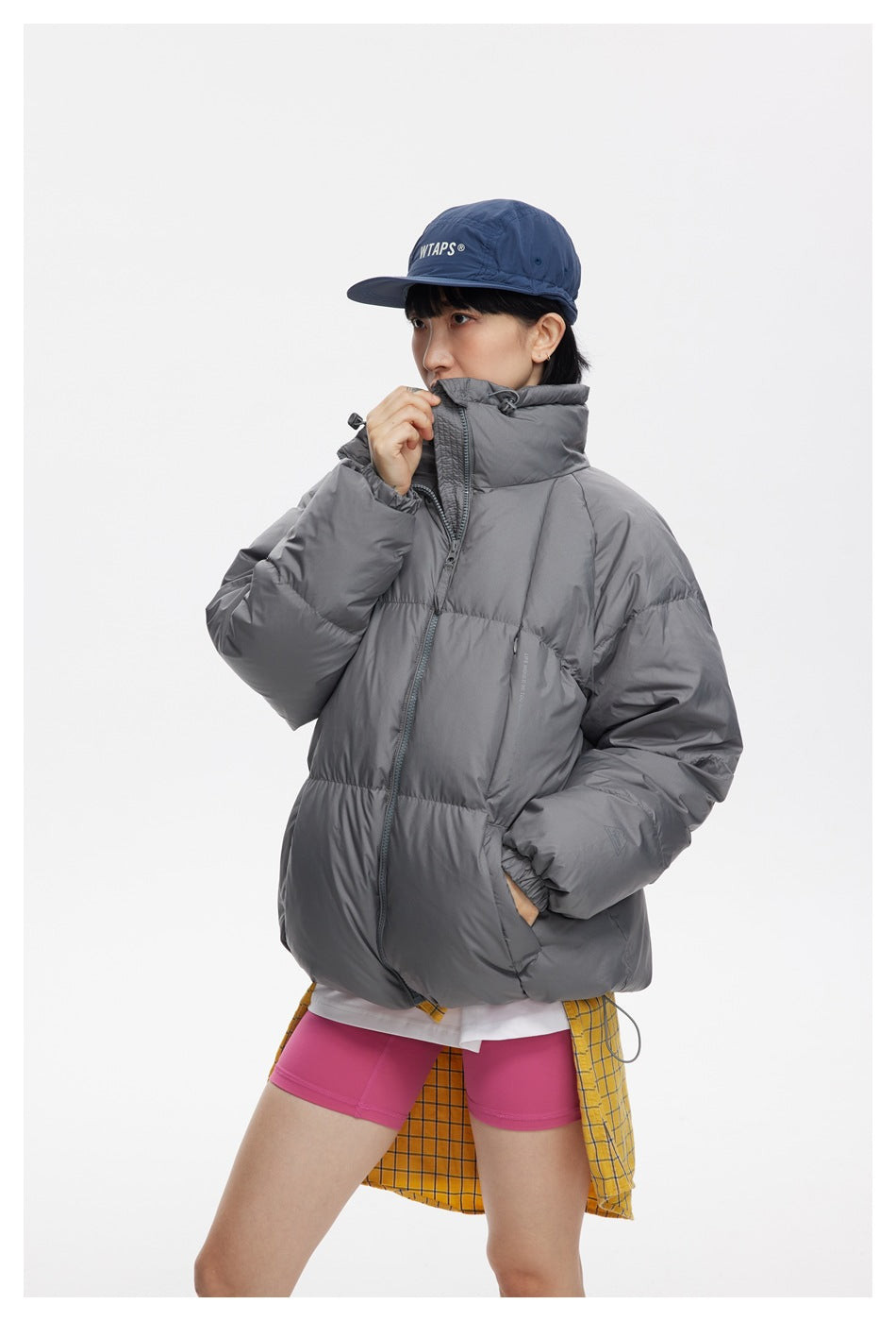 Model wearing an oversized charcoal-gray puffer jacket with a tall collar and front zipper.