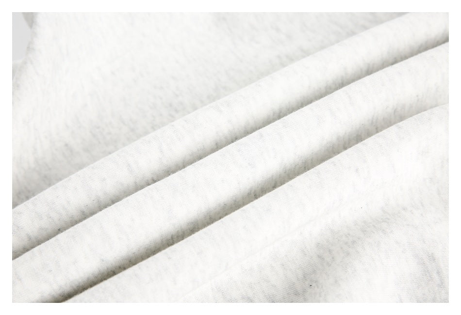 Close-up of the lightly flecked off-white sweatshirt fabric arranged in soft folds.