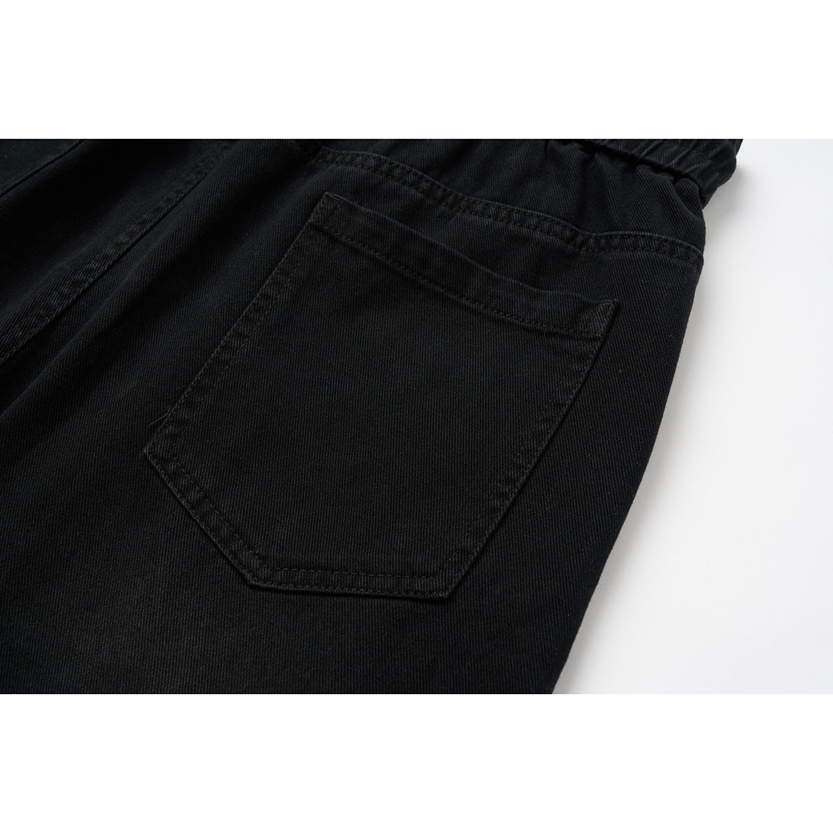 Close-up of a black pants back pocket and surrounding stitching.