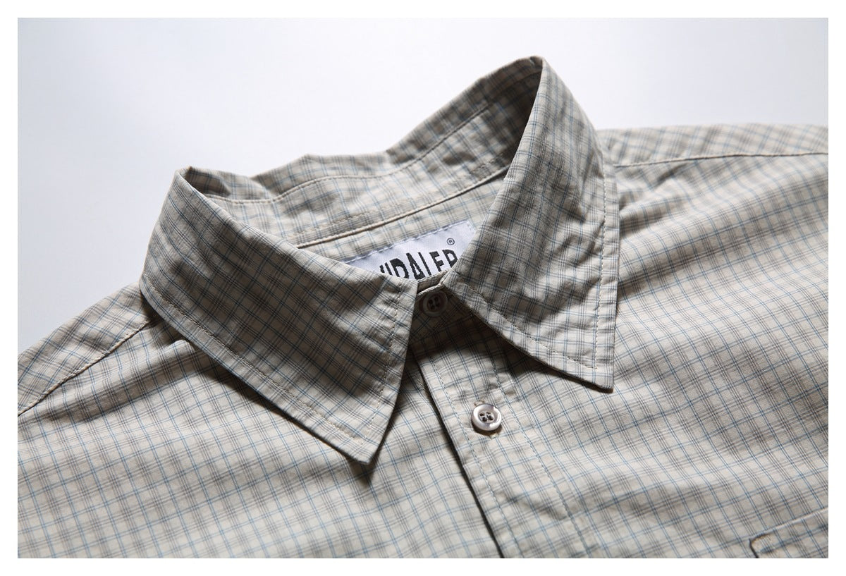 Close-up of the plaid shirt’s pointed collar, top button, and inner neck label.