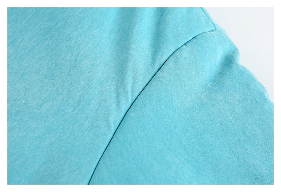 Close-up of turquoise jacket fabric and a curved shoulder seam.