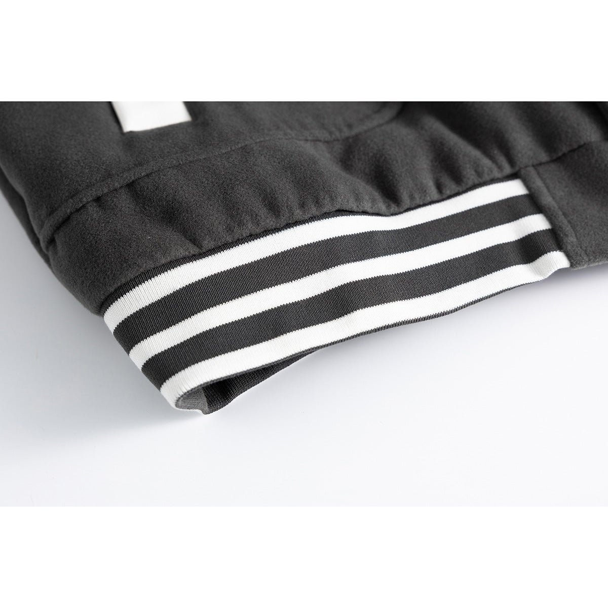 Close-up of a charcoal jacket's cuff with black-and-white striped ribbing.