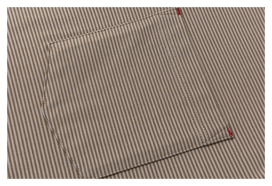 Close-up of a rectangular pocket on beige and brown striped fabric, with small red stitch accents.