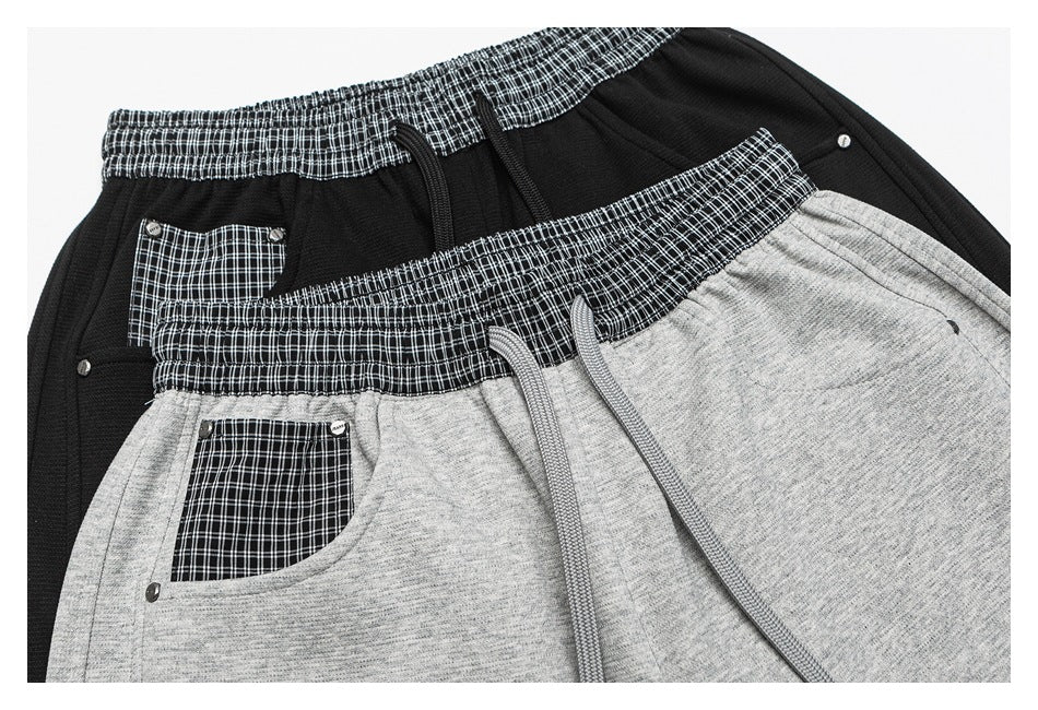 Overlapping black and heather-gray pants show plaid elastic waistbands, matching pocket panels, and gray drawstrings.