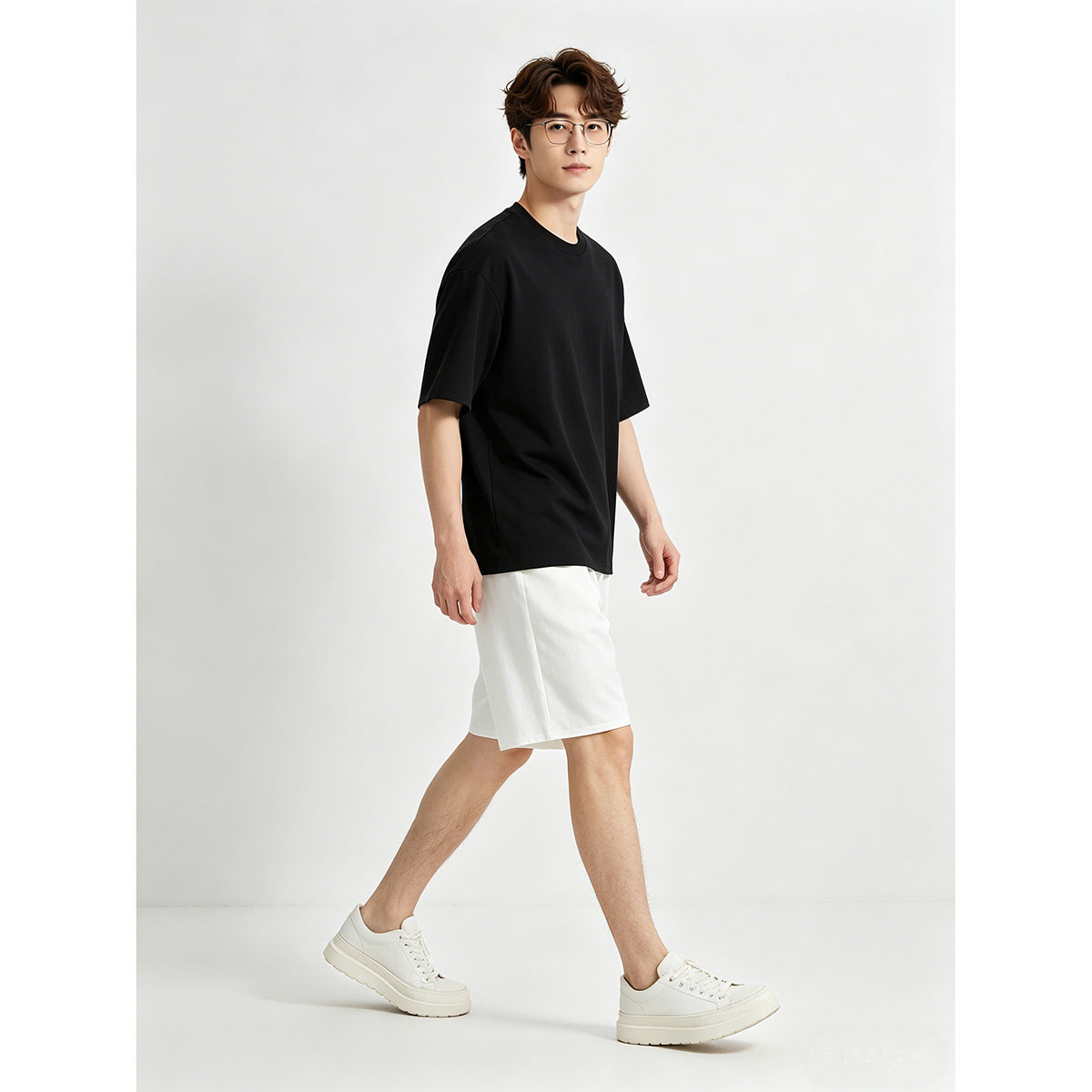 Model wearing an oversized black crew-neck T-shirt, white shorts and white sneakers.