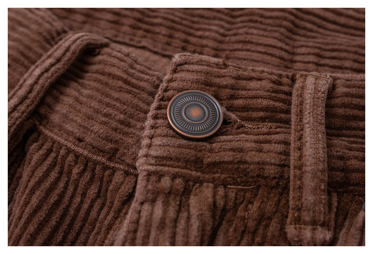 Close-up of a round button and belt loop on the waistband of brown corduroy trousers.