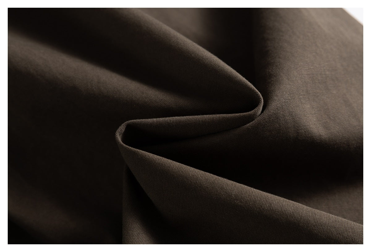 Macro view of dark brown fabric draped in folds, showing its fine woven texture.