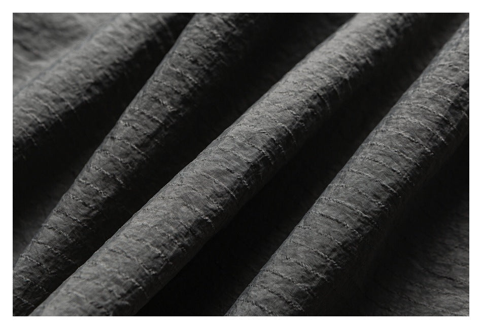Macro view of the charcoal gray garment's crinkled surface and fine grid-like stitching.