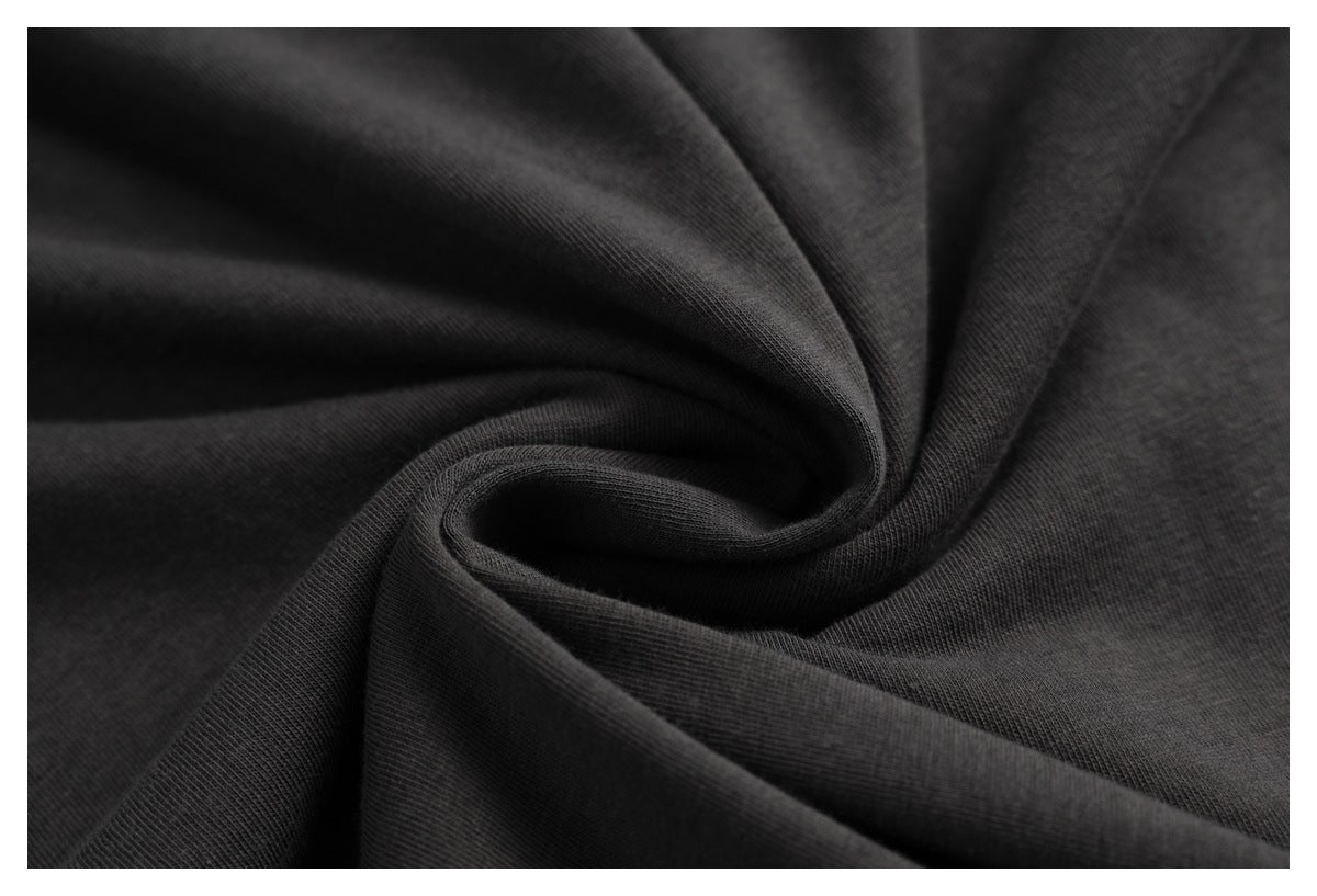 Close-up of charcoal-black fabric gathered into soft folds, showing its surface and texture.