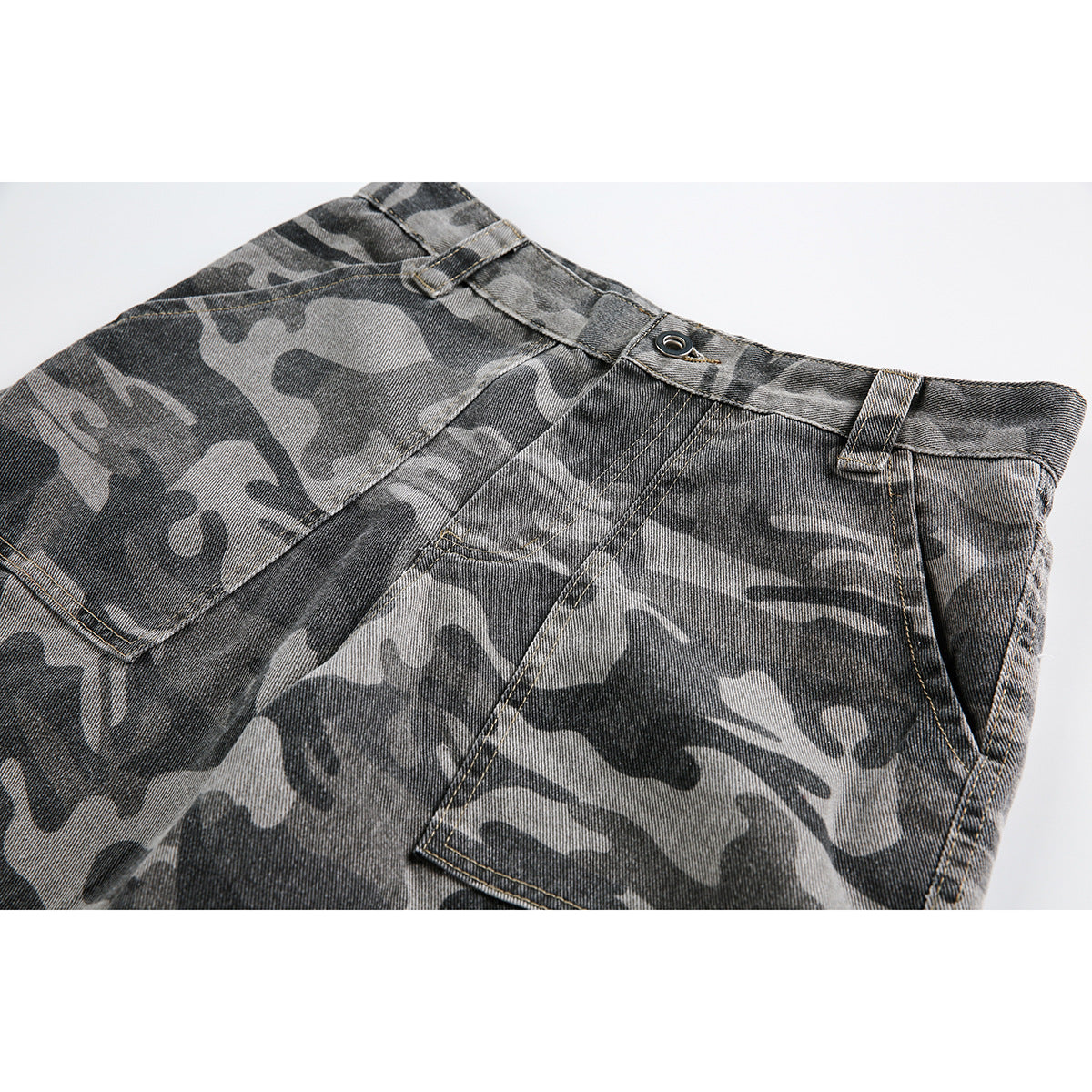 Close-up of gray camouflage shorts showing the front waistband, button, belt loops, fly, and pocket stitching.