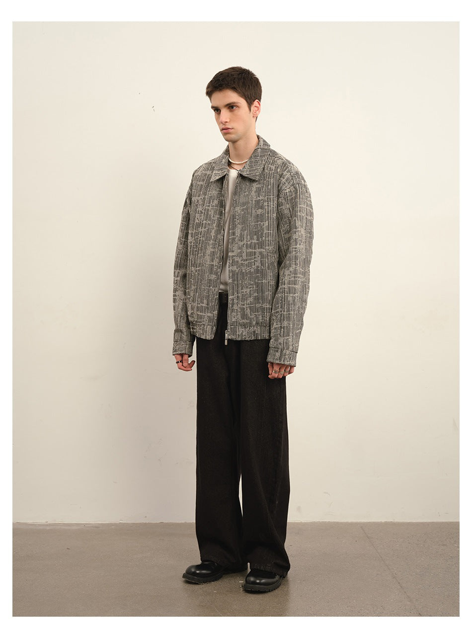 Model wearing a gray abstract-patterned zip-front jacket with black wide-leg pants, shown from a three-quarter angle.