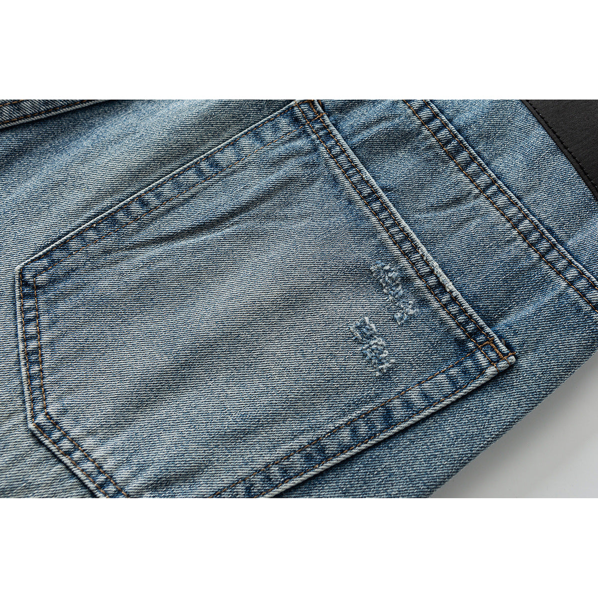 Close-up of a blue faded jeans back pocket with small distressed details.