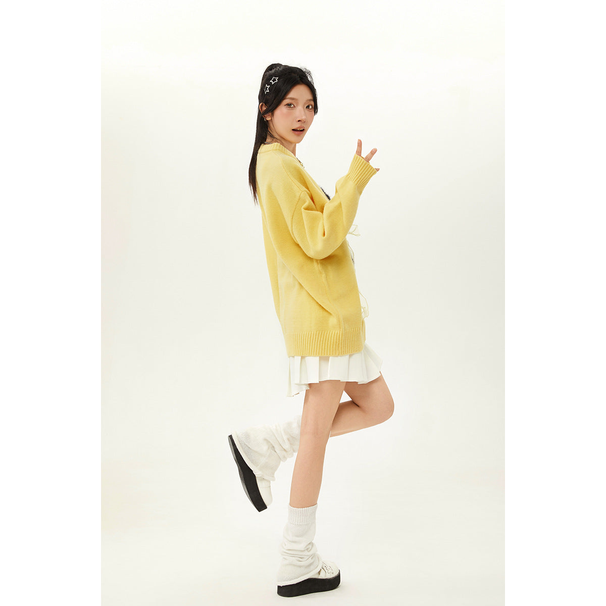 Side view of a model in a yellow oversized sweater, showing its plain back and ribbed hem.