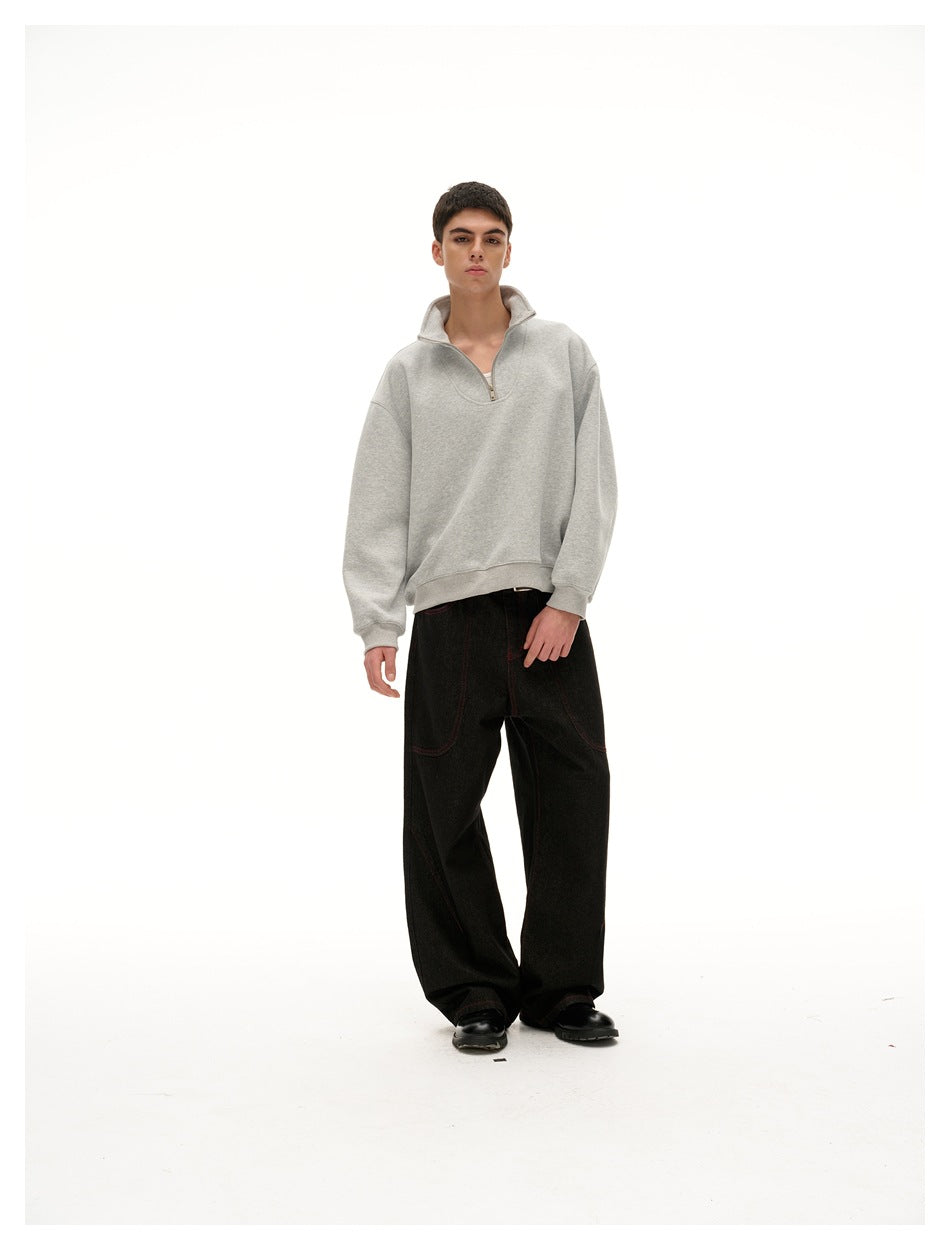 Model wearing a gray half-zip sweatshirt with wide dark jeans and black shoes, full-length front view