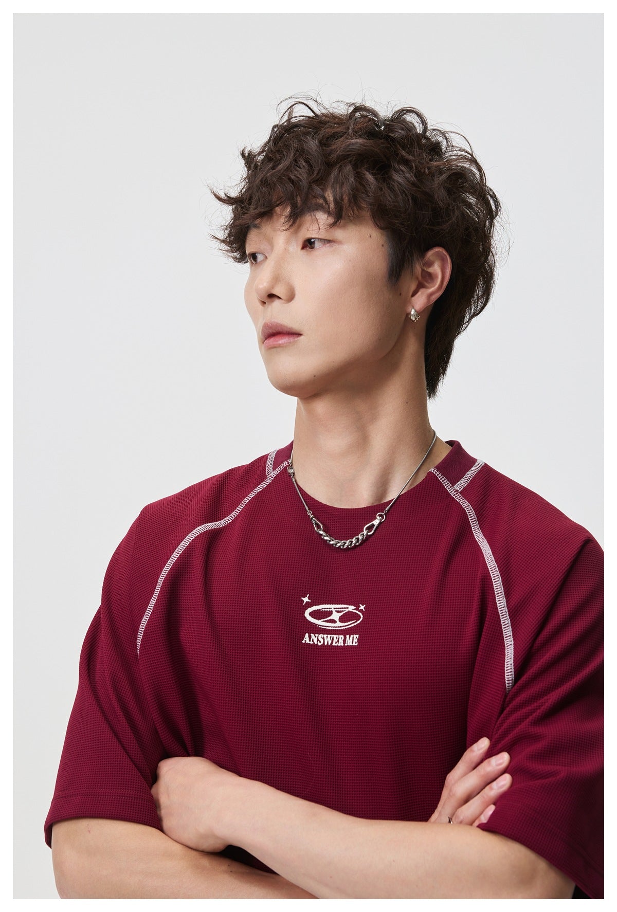 Close view of a model wearing a burgundy shirt, highlighting its contrast seams and small white chest graphic.