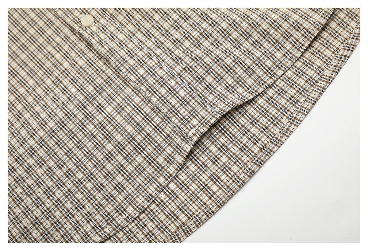 Close-up of a curved stitched edge on a beige and brown checked shirt.
