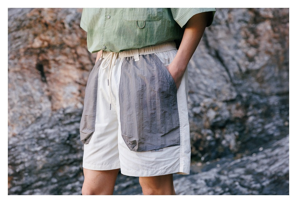 Close front view of ivory shorts with a drawstring waist and oversized gray flap pockets.