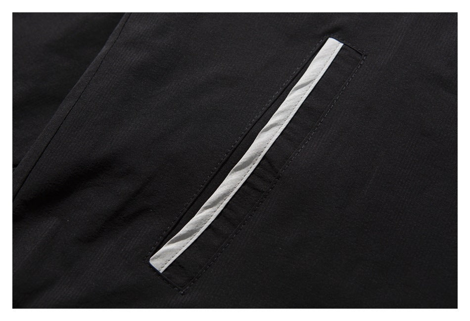 Close-up of a black garment's slanted pocket with a narrow white trim.