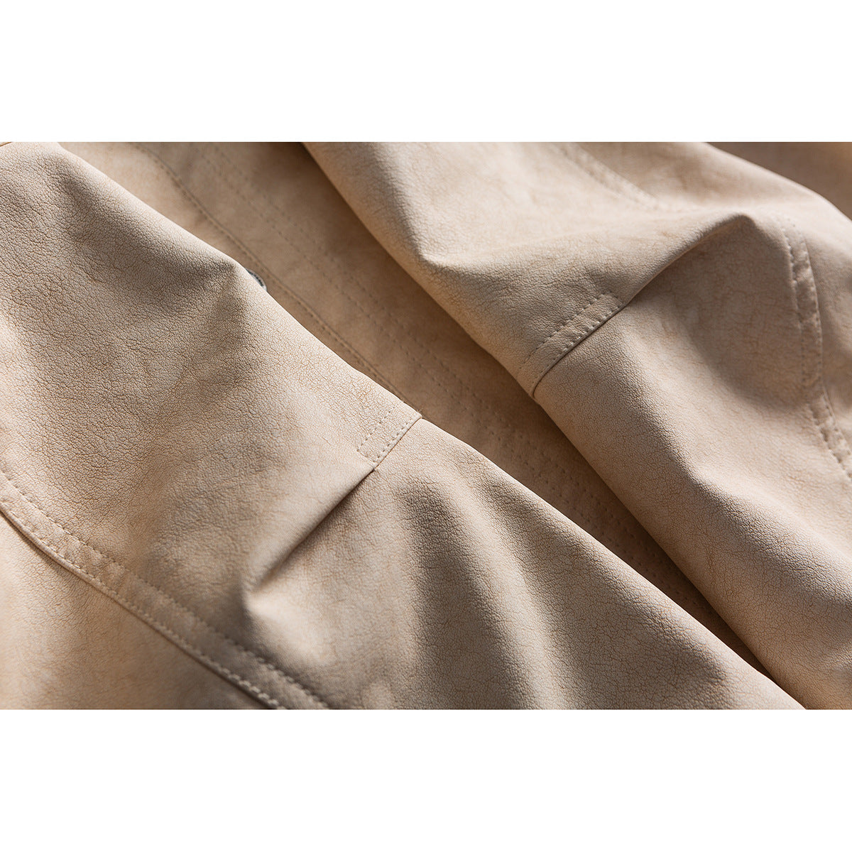 Close-up of beige jacket fabric, overlapping panels, and stitched seams.