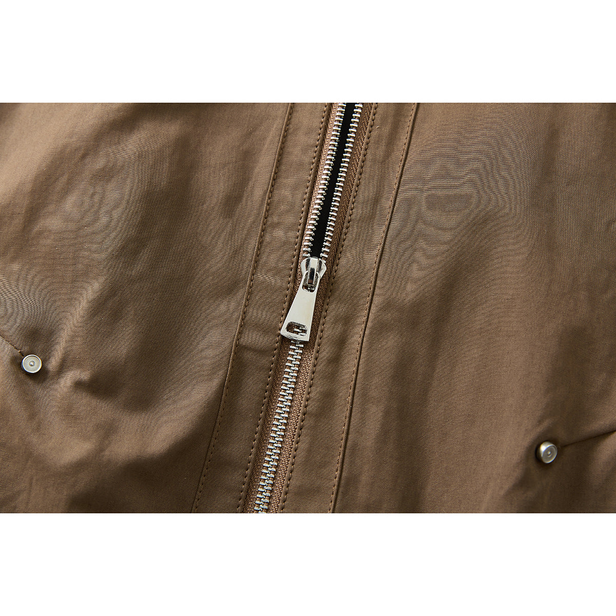 Close-up of a brown jacket's silver front zipper and snap details.