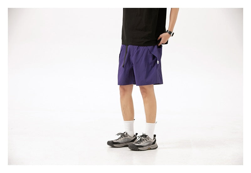 Model wearing purple drawstring shorts with side pockets, shown at a three-quarter angle.