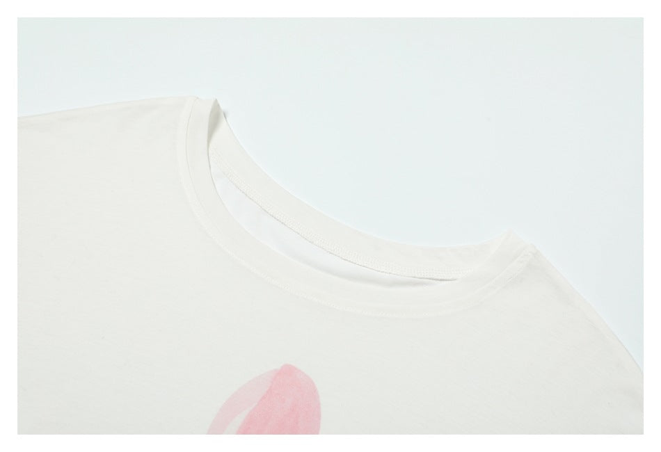 Close-up of a white T-shirt crew neckline with a small portion of pink artwork visible below.