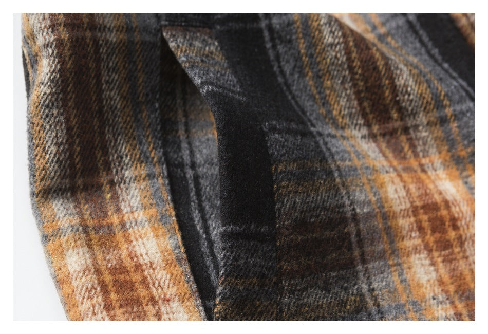 Close-up of layered fabric edges and stitching on a charcoal and rust plaid garment.
