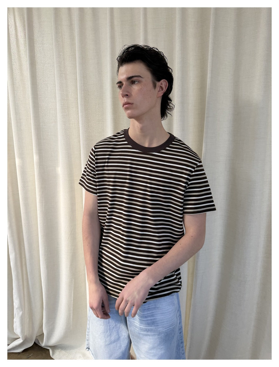 Closer front view of a model wearing a dark brown and cream striped short-sleeve T-shirt.