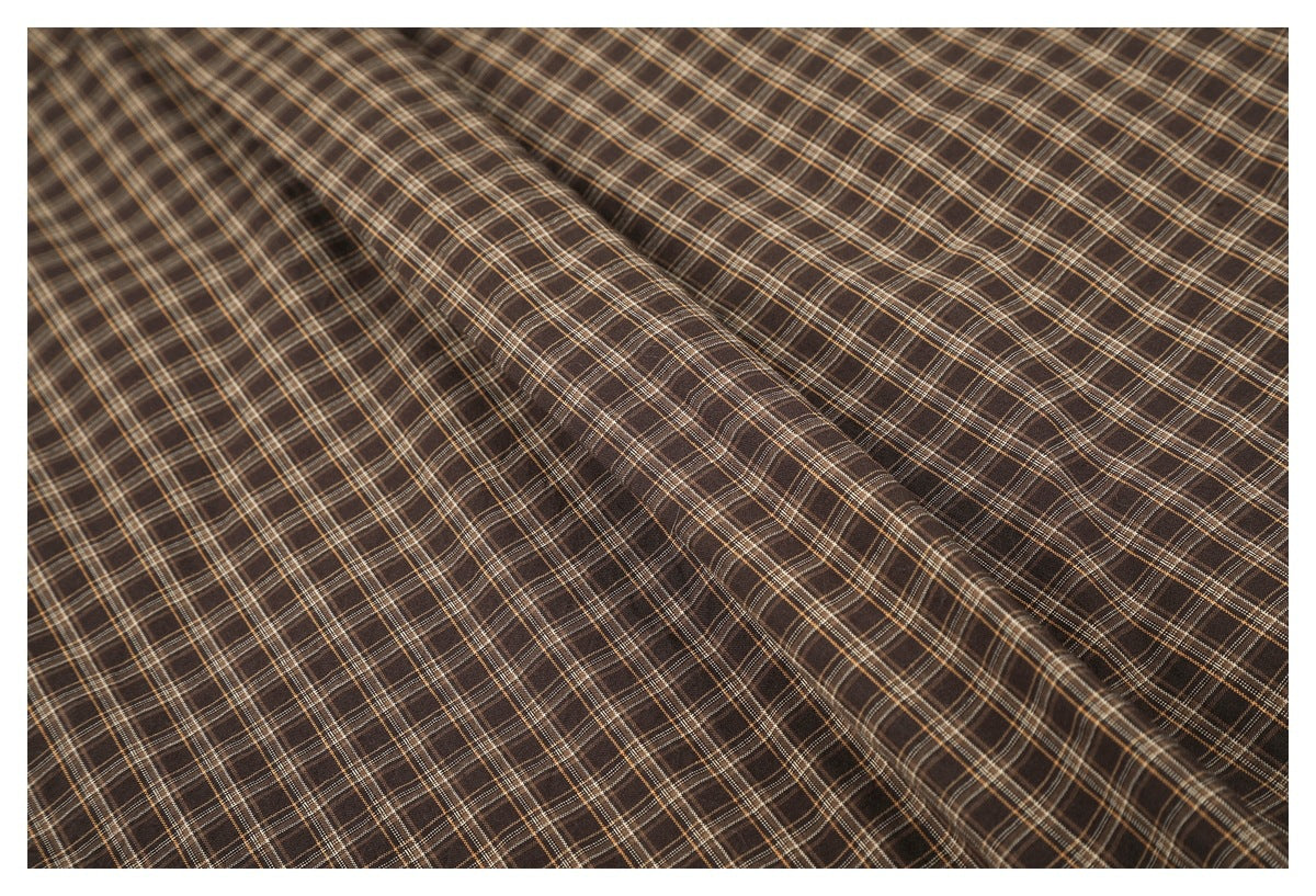 Close view of brown plaid fabric draped in soft folds.