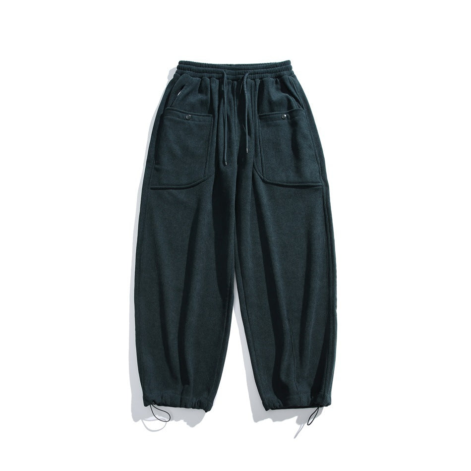 Dark green relaxed pants flat lay with drawstring waist, large snap-button front pockets and drawstring hems