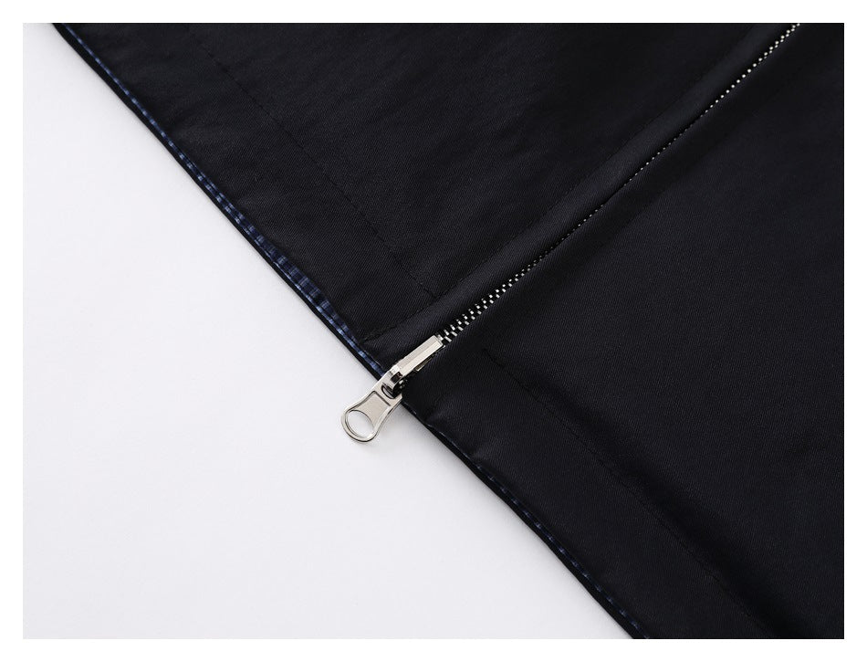 Close-up of a silver zipper and dark plaid lining on a black garment.