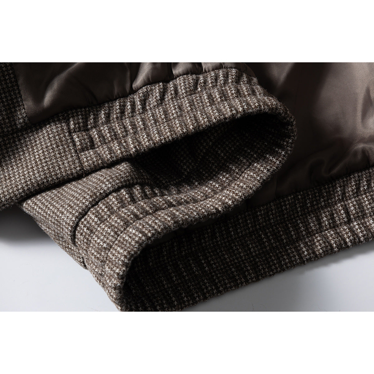 Close-up of the jacket's houndstooth waistband and dark lining, showing the gathered hem and inner construction.