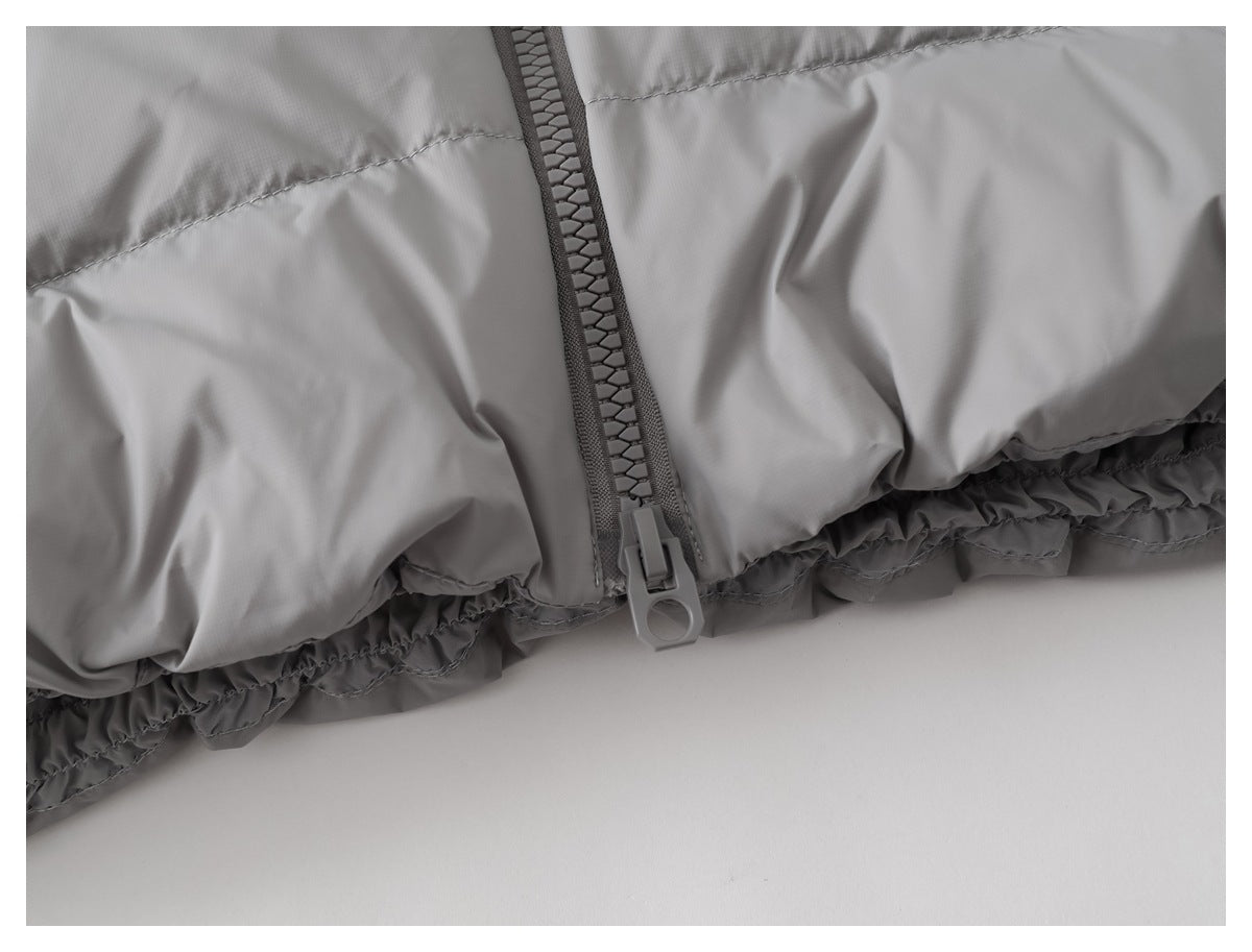 Close-up of a chunky zipper and gathered hem on a gray padded garment.