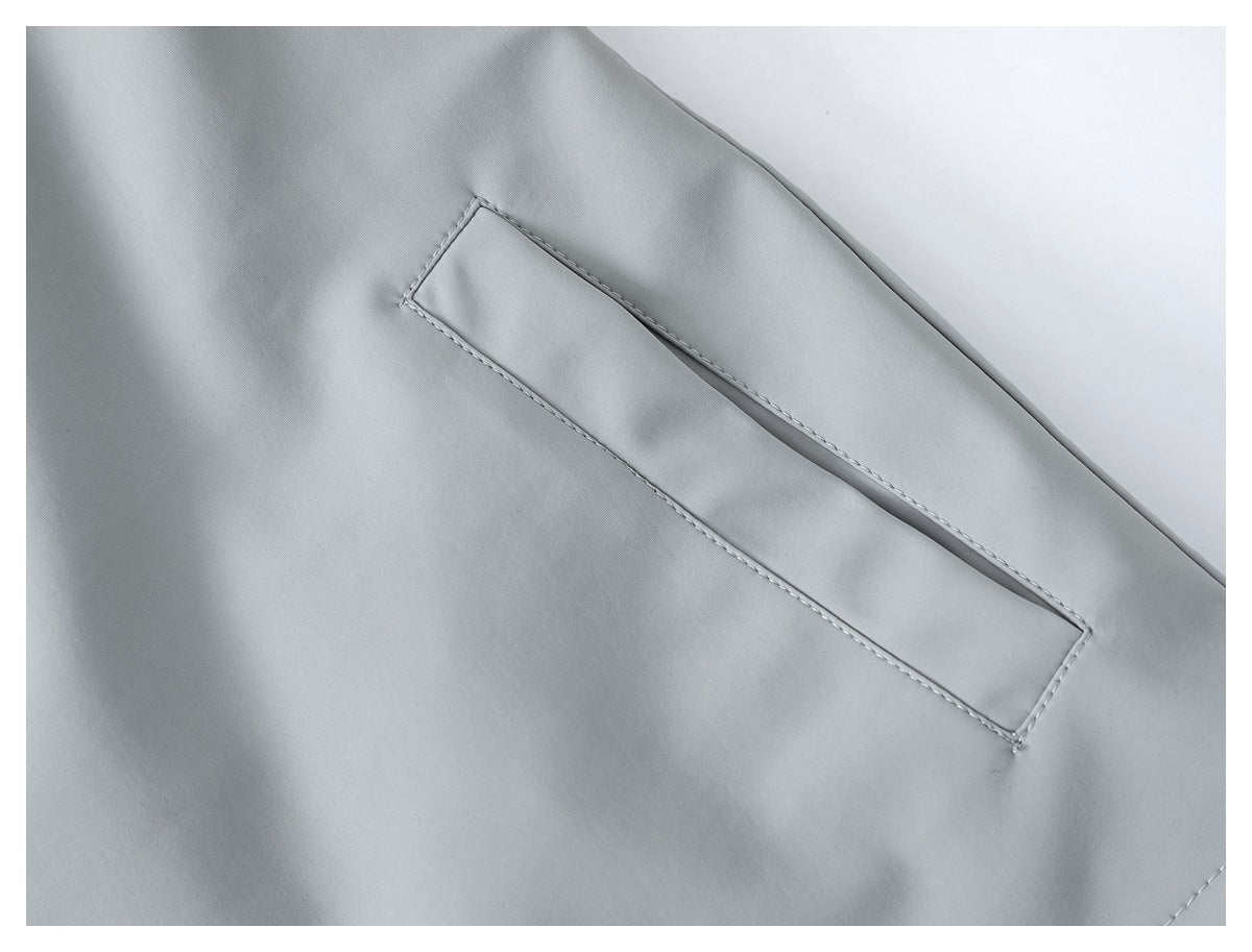 Close-up of a narrow welt pocket on light gray jacket fabric.