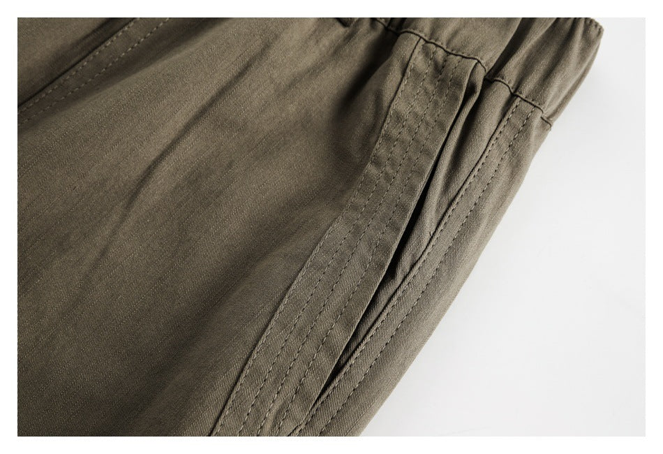 Close-up of olive-brown trousers showing a side seam and gathered elastic waistband.