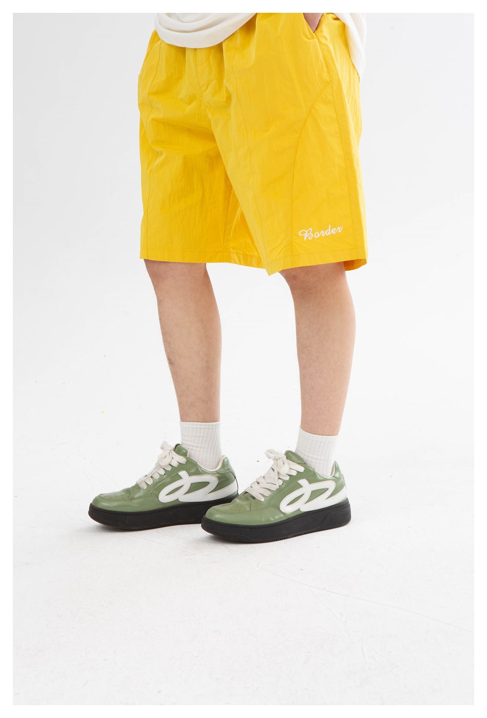 Close view of bright yellow shorts with side pockets and small white script near the hem.