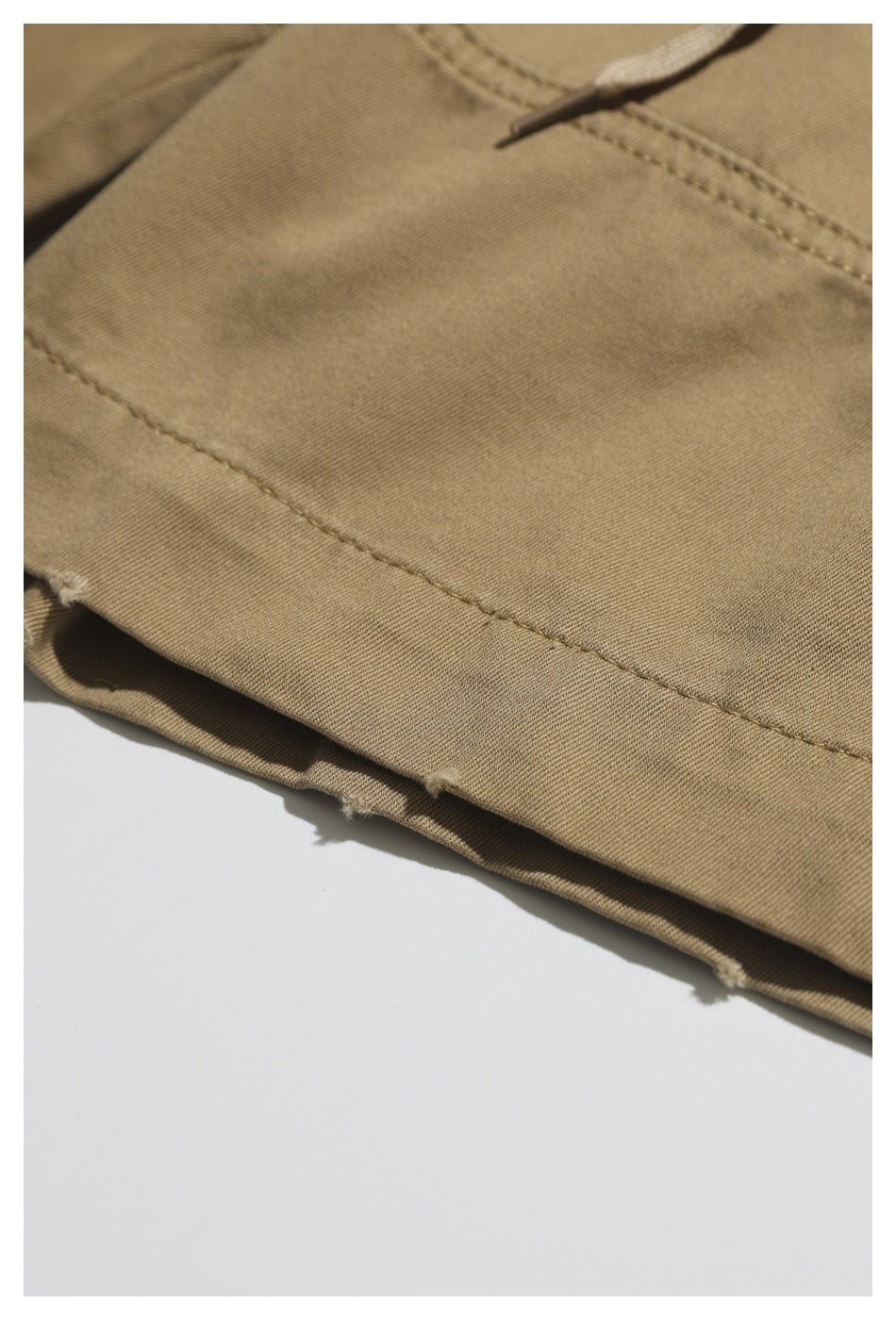 Close-up of khaki trouser fabric and a stitched seam along the hem.