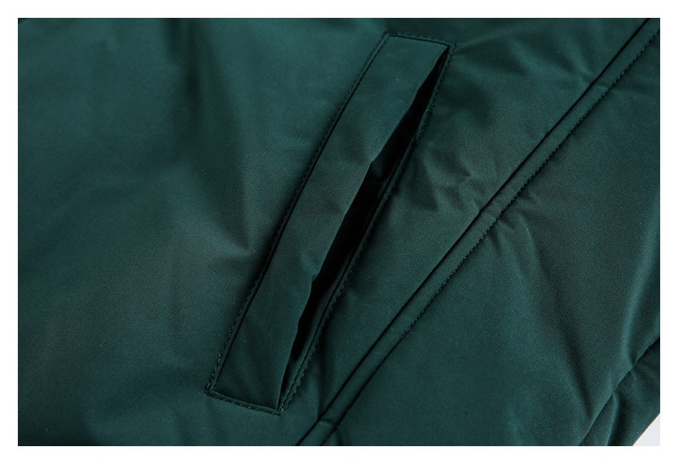 Close-up of a dark green jacket’s narrow welt pocket and diagonal seam.