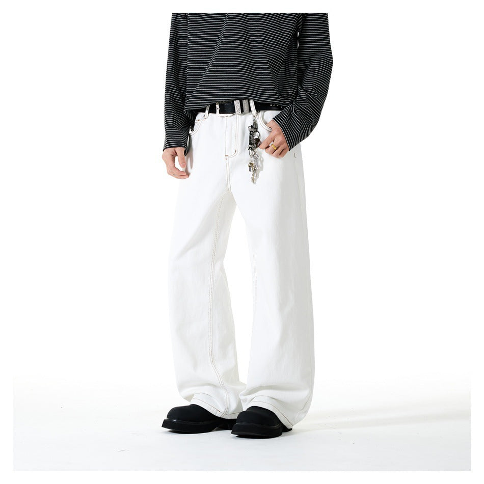 Person wearing white straight wide-leg jeans with a belt, key chain and striped top, with one hand in pocket