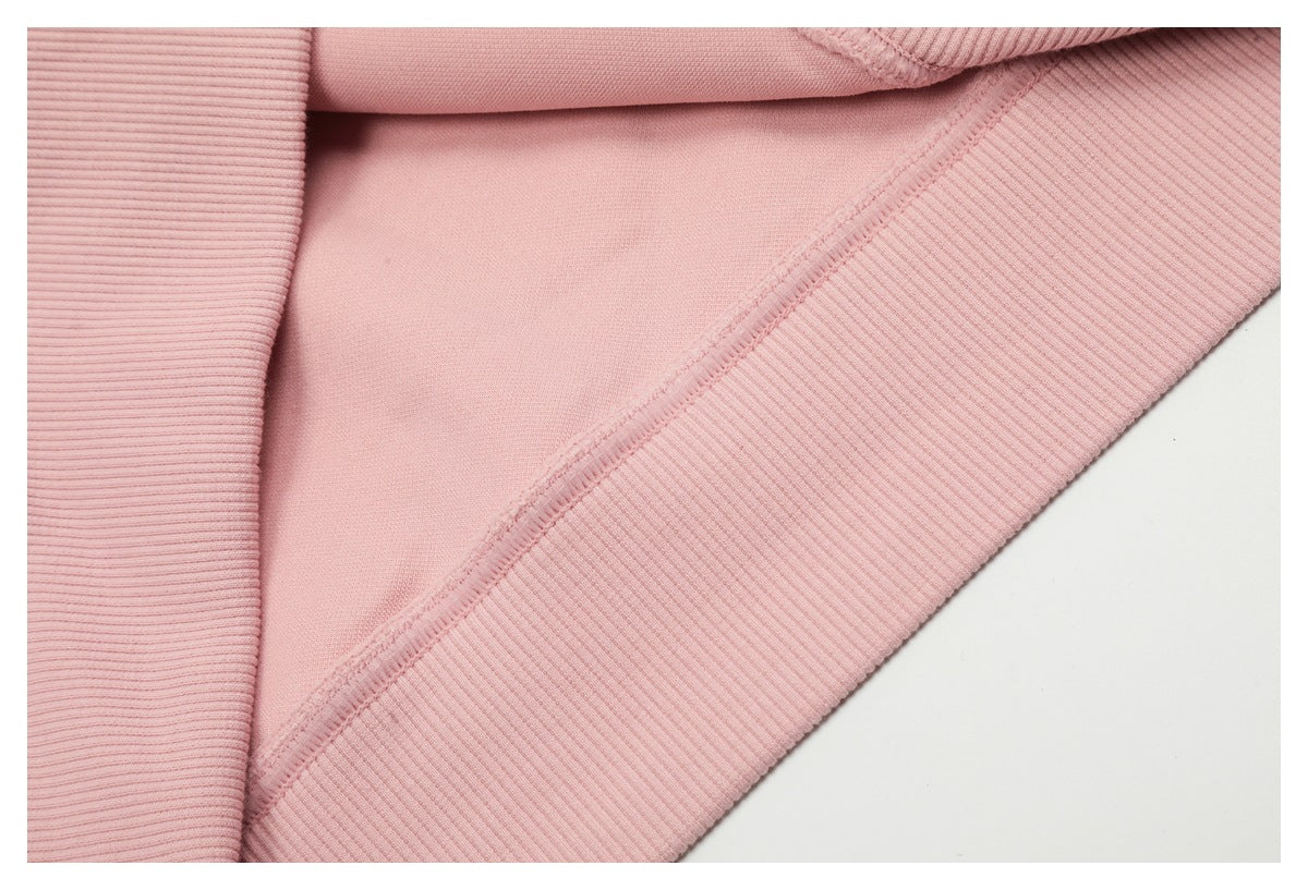 Close-up of pale pink garment fabric, an overlocked seam, and rib-knit edge.