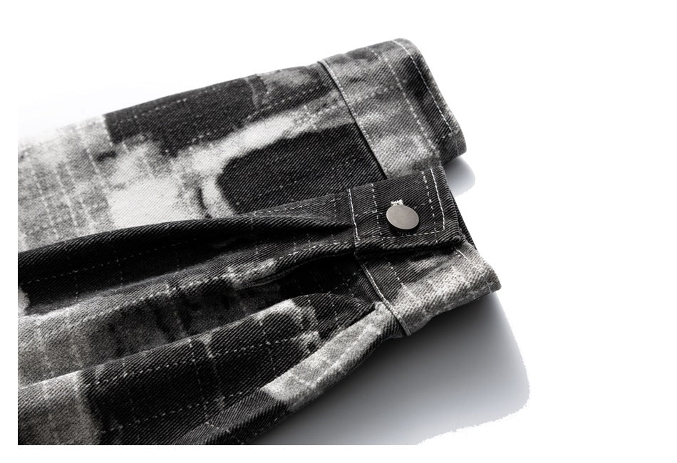 Close-up of a folded black-and-gray abstract-print garment showing a cuff tab with a metal snap.