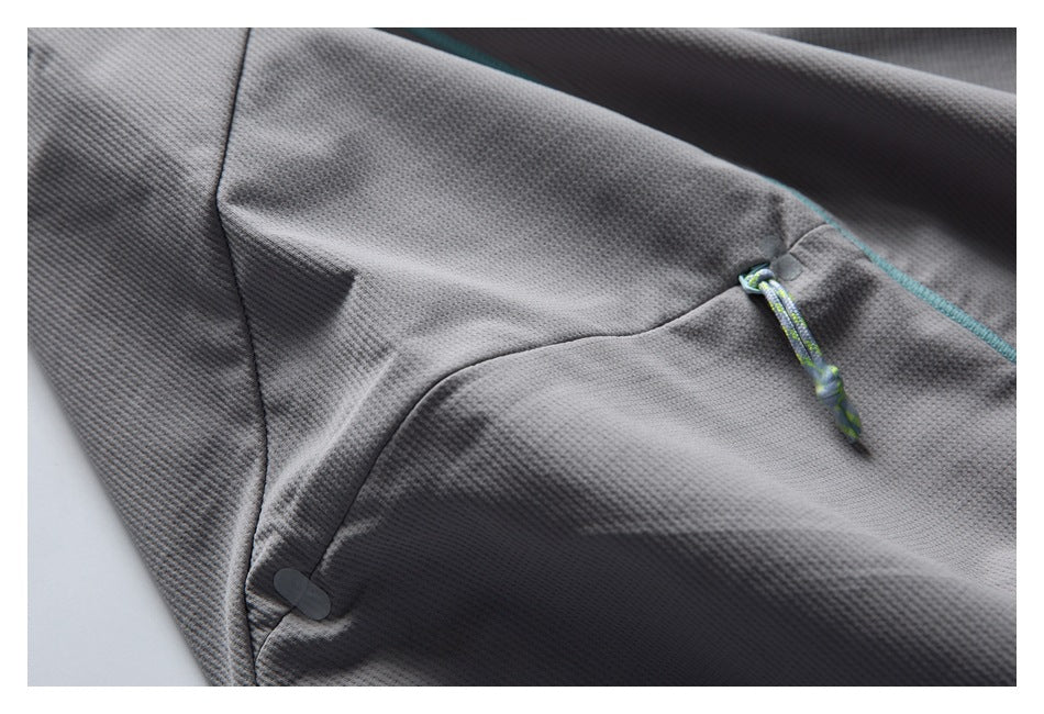 Gray garment pocket close-up with a patterned drawcord and turquoise seam piping.