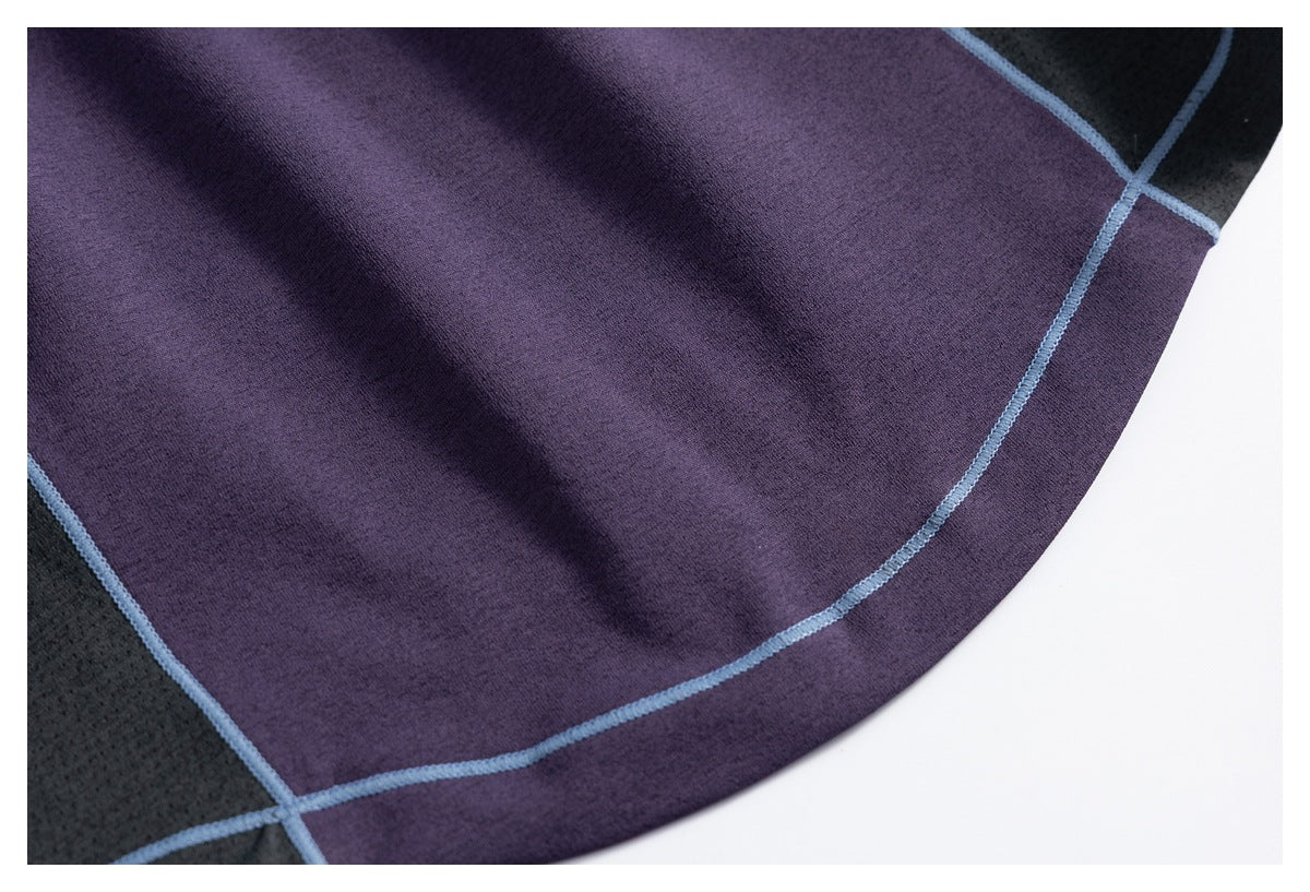 Close-up of the purple fabric panel, curved hem, and pale blue seam piping beside black fabric.