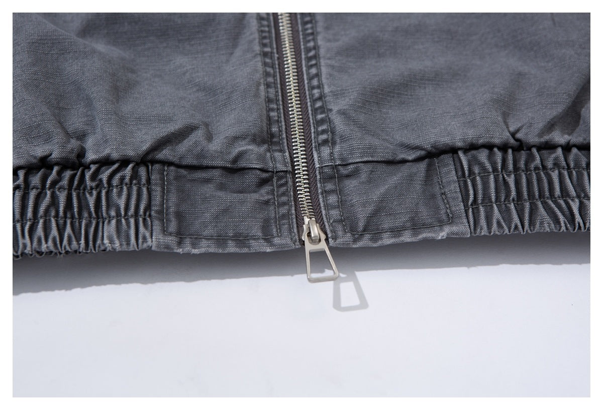 Close-up of the jacket's elasticated hem and front zipper in charcoal gray.