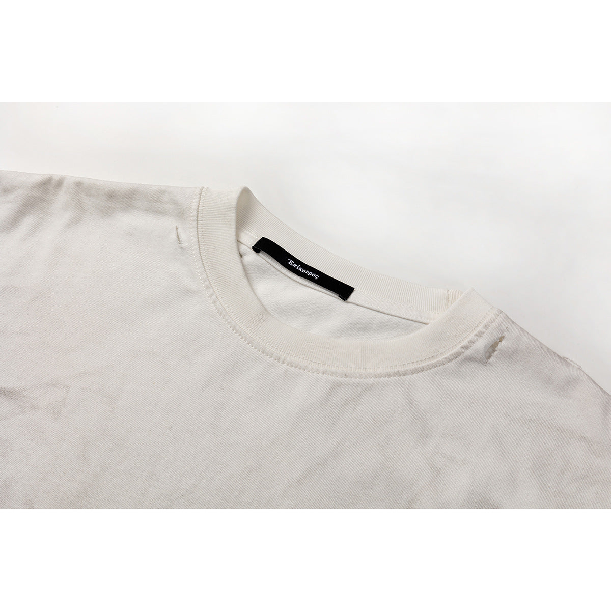 Close-up of a pale gray T-shirt neckline with ribbed crew collar and a black inner neck label.