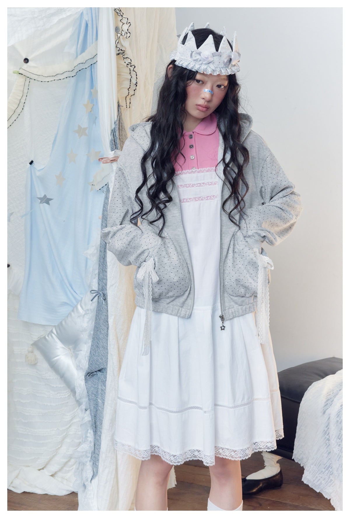 Front view of a model wearing a light gray dotted hoodie over a white dress with a pink collar.