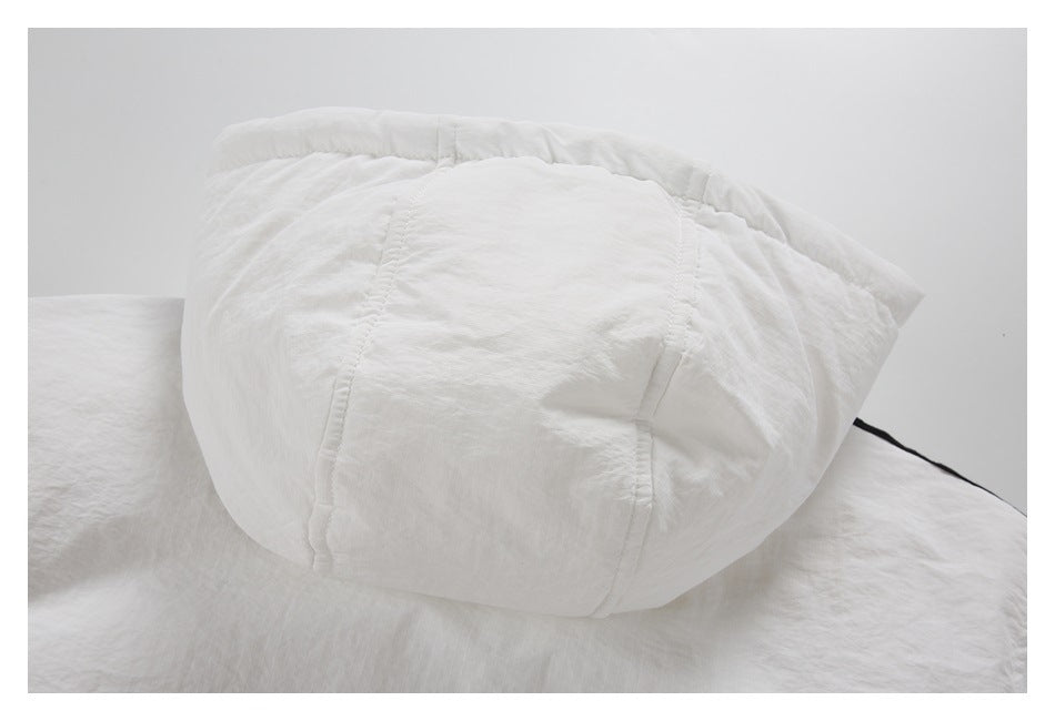 Close-up of a rounded white garment section with stitched panel seams and a gathered edge.