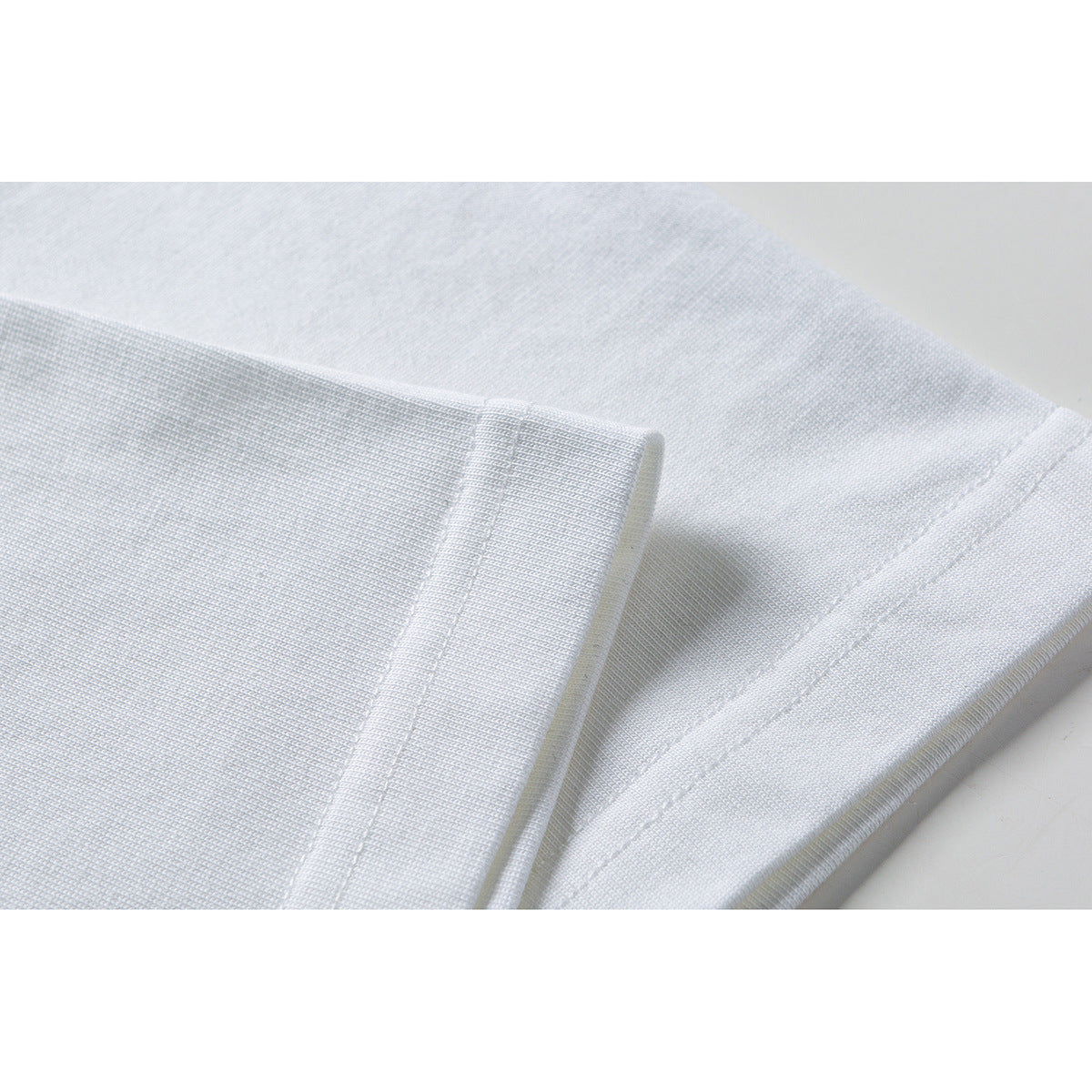 Close-up of a white T-shirt sleeve hem and stitched seam.
